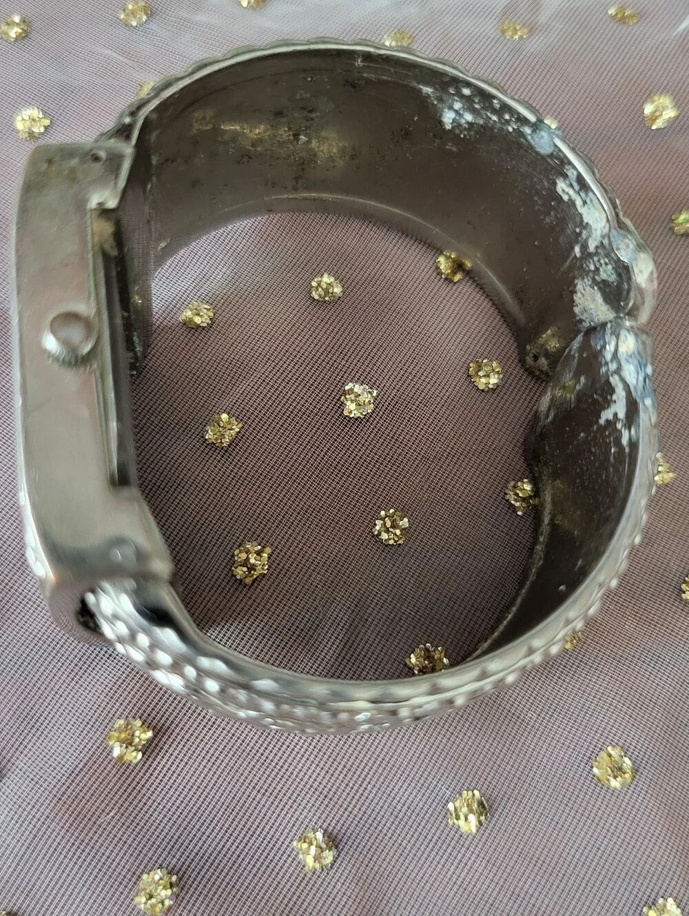 Silver bracelet watch with ornate scrollwork design has antique white face